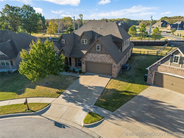 view of front of house with a front lawn, central AC unit, and a garage