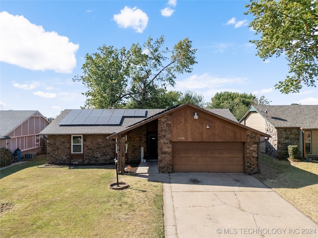 ranch-style house featuring a front yard, a garage, central AC, and solar panels