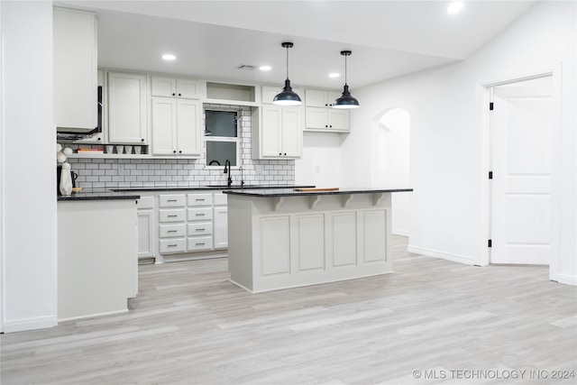 kitchen with white cabinetry, a center island, decorative light fixtures, and light hardwood / wood-style floors