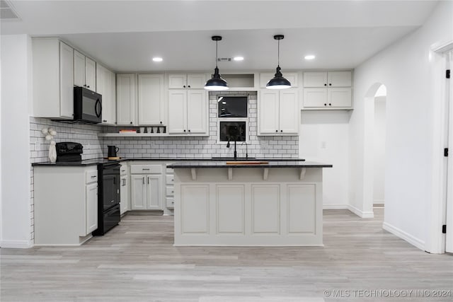 kitchen featuring black appliances, a center island, pendant lighting, white cabinets, and light hardwood / wood-style floors