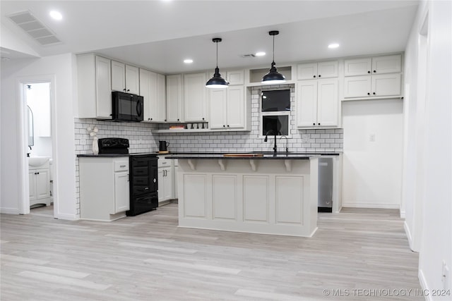 kitchen featuring black appliances, light wood-type flooring, a center island, white cabinetry, and pendant lighting