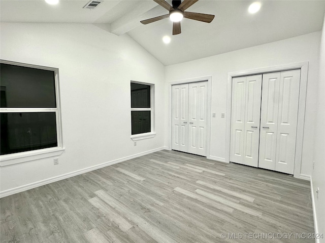 unfurnished bedroom with lofted ceiling with beams, light hardwood / wood-style flooring, two closets, and ceiling fan