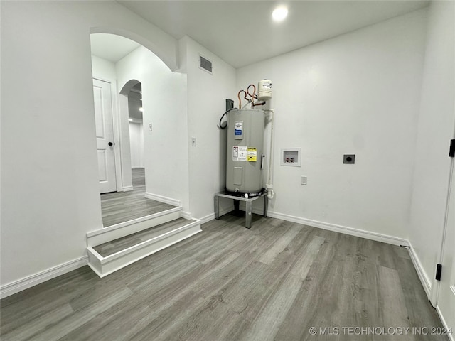 washroom featuring hookup for an electric dryer, water heater, hardwood / wood-style flooring, and washer hookup