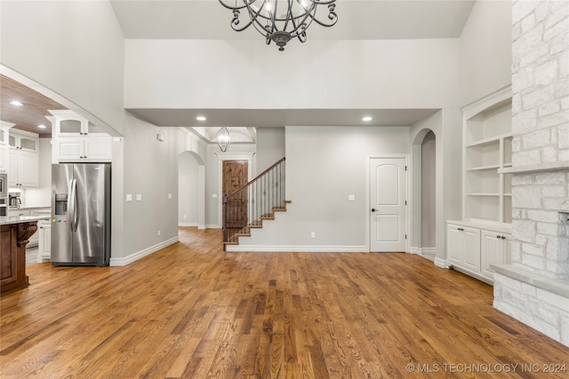 unfurnished living room featuring hardwood / wood-style floors, a high ceiling, and built in shelves