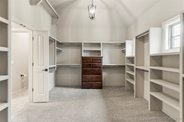 spacious closet with vaulted ceiling and light colored carpet