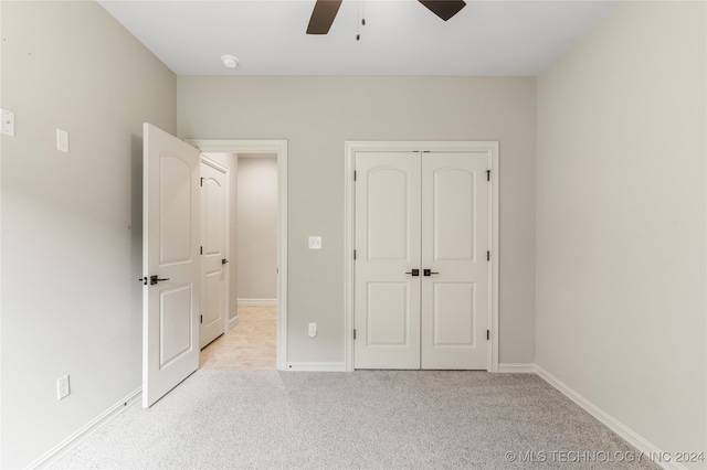 unfurnished bedroom with a closet, light colored carpet, and ceiling fan