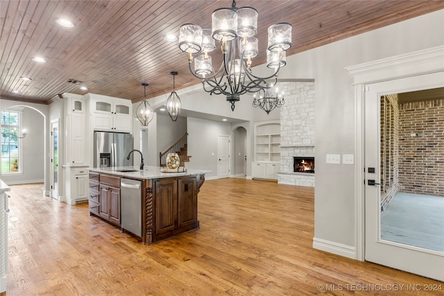 kitchen with appliances with stainless steel finishes, white cabinetry, a kitchen island with sink, wood-type flooring, and built in shelves