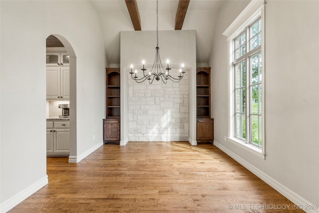 unfurnished dining area featuring a wealth of natural light, a chandelier, vaulted ceiling with beams, and light hardwood / wood-style floors