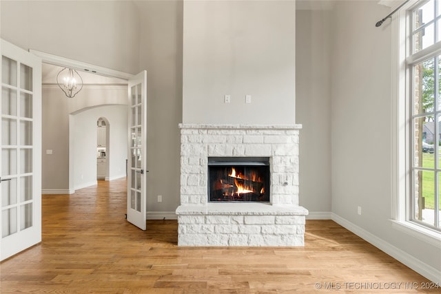 unfurnished living room with a stone fireplace, french doors, hardwood / wood-style floors, and a healthy amount of sunlight