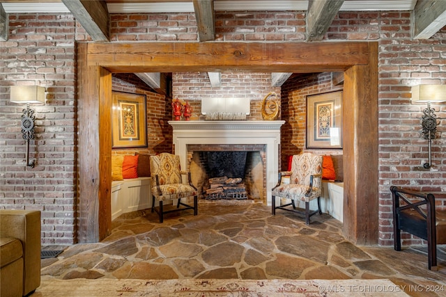 sitting room with beam ceiling, brick wall, and a fireplace