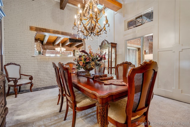 carpeted dining area with a towering ceiling, beamed ceiling, brick wall, and plenty of natural light