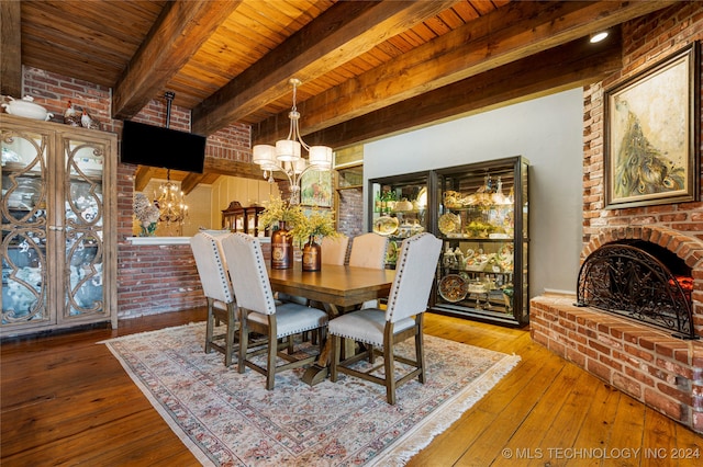 dining room with beamed ceiling, wood-type flooring, wooden ceiling, brick wall, and an inviting chandelier