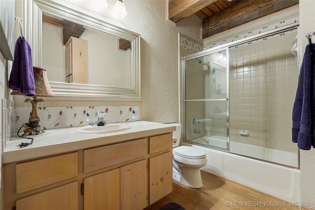 full bathroom with hardwood / wood-style floors, decorative backsplash, combined bath / shower with glass door, toilet, and vanity