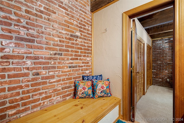 hall featuring brick wall and carpet flooring