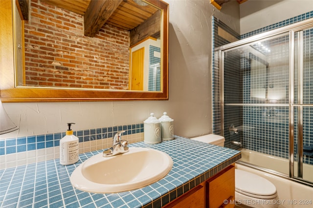 full bathroom with beamed ceiling, vanity, combined bath / shower with glass door, and toilet