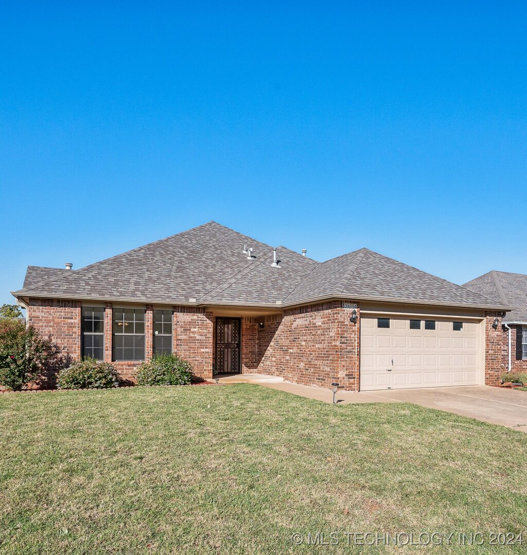 ranch-style home featuring a garage and a front lawn