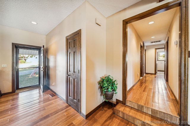 corridor featuring wood-type flooring and a textured ceiling