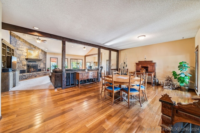 dining area with a fireplace, light wood-type flooring, vaulted ceiling with beams, and ceiling fan