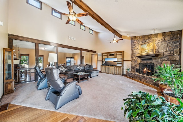 living room with beamed ceiling, a stone fireplace, wood-type flooring, and high vaulted ceiling