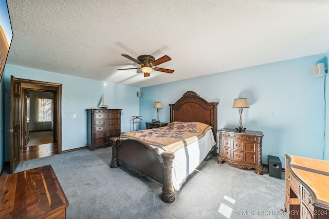 bedroom with carpet, a textured ceiling, and ceiling fan