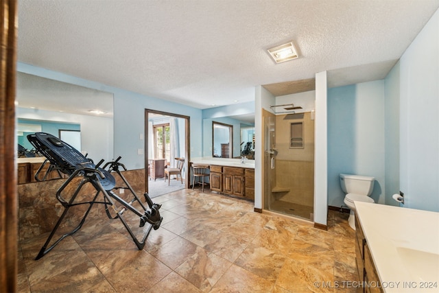 bathroom with vanity, toilet, a shower with door, and a textured ceiling