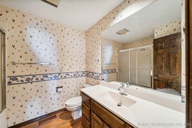 bathroom featuring a textured ceiling, toilet, an enclosed shower, vanity, and hardwood / wood-style flooring