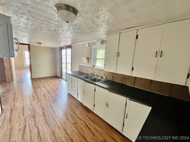 kitchen featuring dark countertops, a sink, white cabinetry, and light wood-style floors