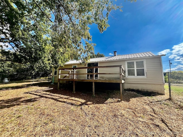 back of house with a deck, a fenced backyard, and metal roof