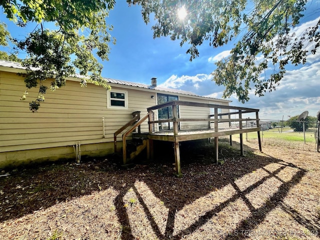 rear view of house with fence, a deck, and metal roof