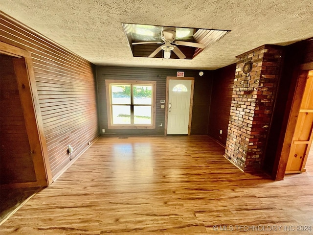 interior space with a textured ceiling, wood finished floors, brick wall, and a ceiling fan