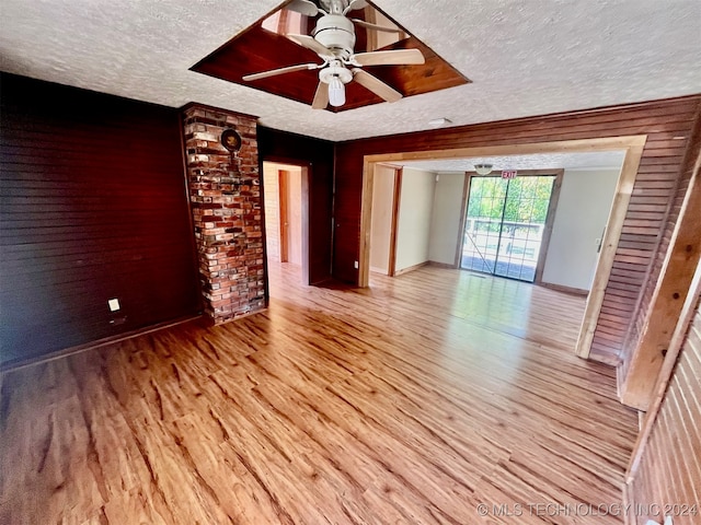 unfurnished living room with a textured ceiling, light wood-type flooring, and ceiling fan