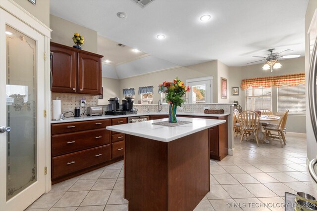 kitchen with decorative backsplash, light tile patterned floors, ceiling fan, crown molding, and a center island