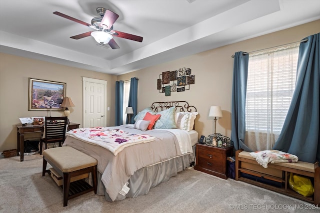 carpeted bedroom featuring a closet, ceiling fan, and a tray ceiling