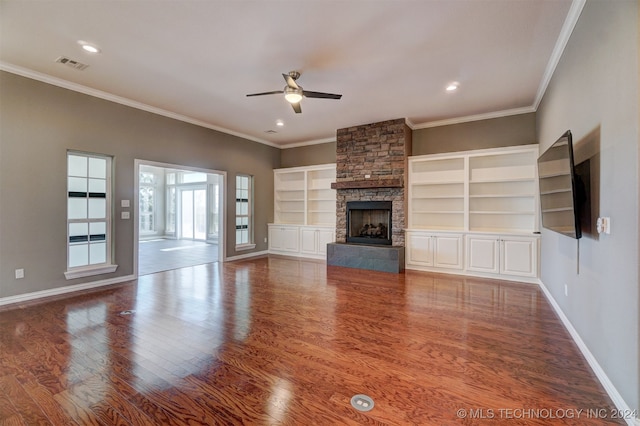 unfurnished living room with crown molding, a stone fireplace, wood-type flooring, and ceiling fan