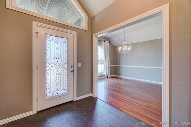 entrance foyer featuring vaulted ceiling, an inviting chandelier, and dark hardwood / wood-style flooring