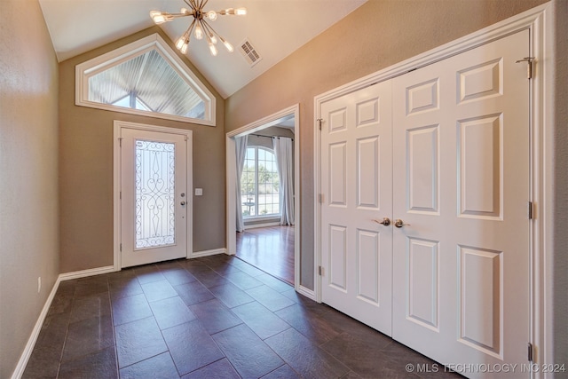 foyer entrance with lofted ceiling, a notable chandelier, and a healthy amount of sunlight