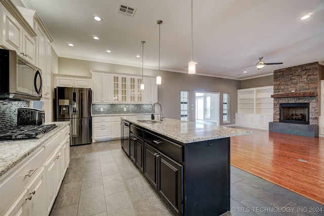 kitchen with appliances with stainless steel finishes, tasteful backsplash, decorative light fixtures, and a center island with sink