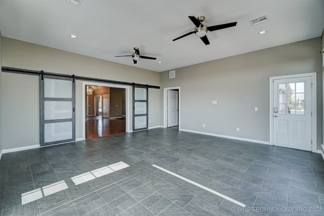 unfurnished living room featuring ceiling fan and a barn door