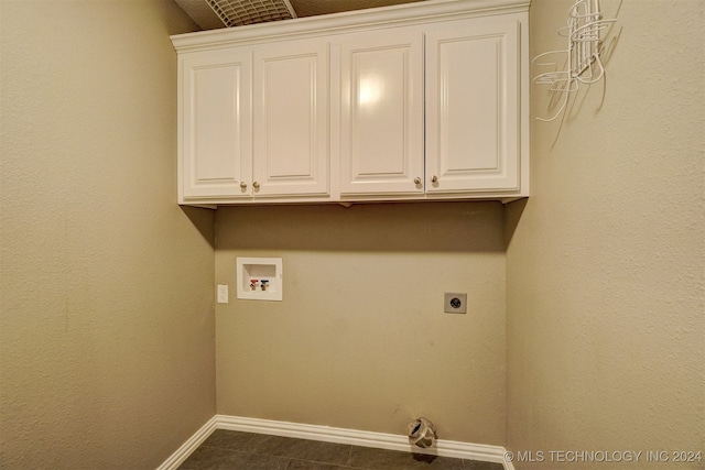 laundry room with dark tile patterned flooring, electric dryer hookup, washer hookup, and cabinets