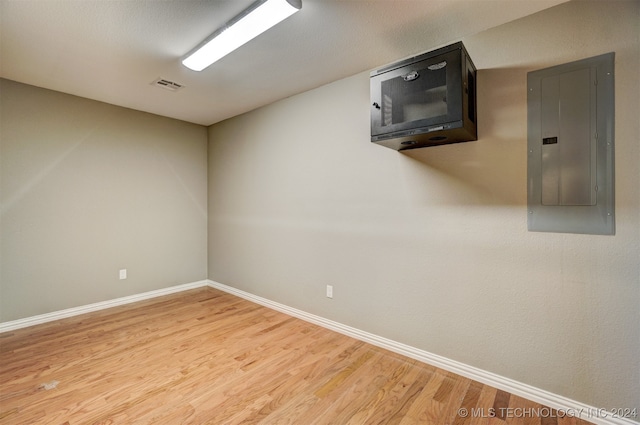 empty room featuring electric panel and light hardwood / wood-style floors