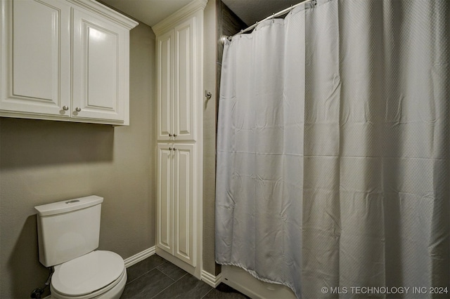 bathroom featuring toilet and curtained shower