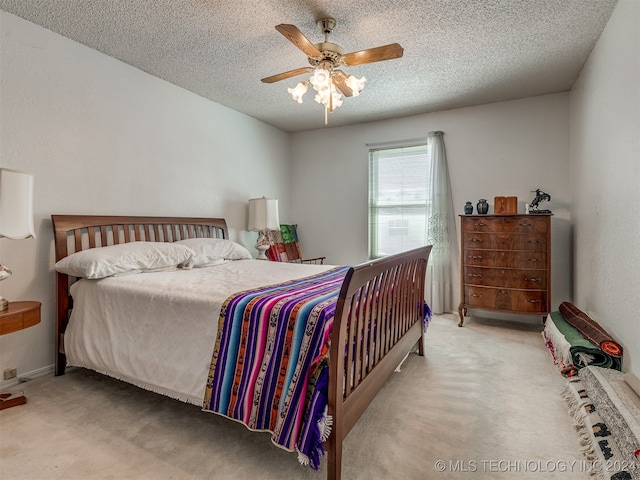 carpeted bedroom featuring ceiling fan and a textured ceiling