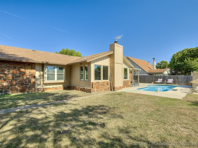 back of property featuring a lawn and a fenced in pool