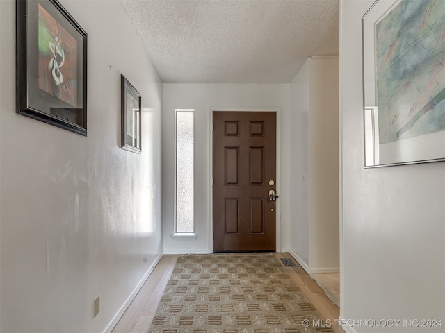 foyer entrance with a textured ceiling and light wood-type flooring