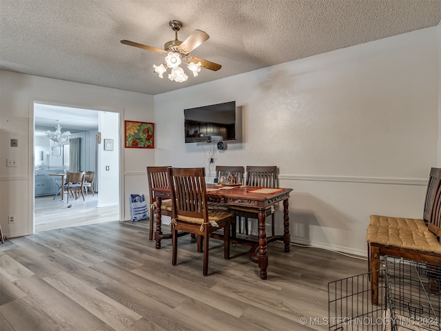 dining room with hardwood / wood-style flooring, a textured ceiling, and ceiling fan with notable chandelier