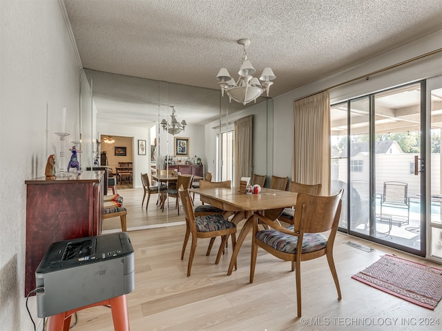 dining room with light hardwood / wood-style flooring, a notable chandelier, and a textured ceiling