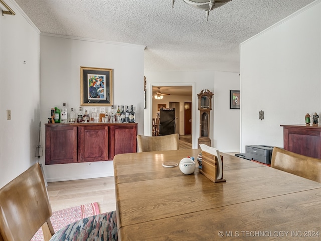 dining room with ceiling fan, crown molding, a textured ceiling, and light wood-type flooring