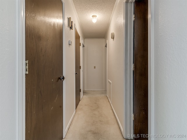 corridor with a textured ceiling and light colored carpet