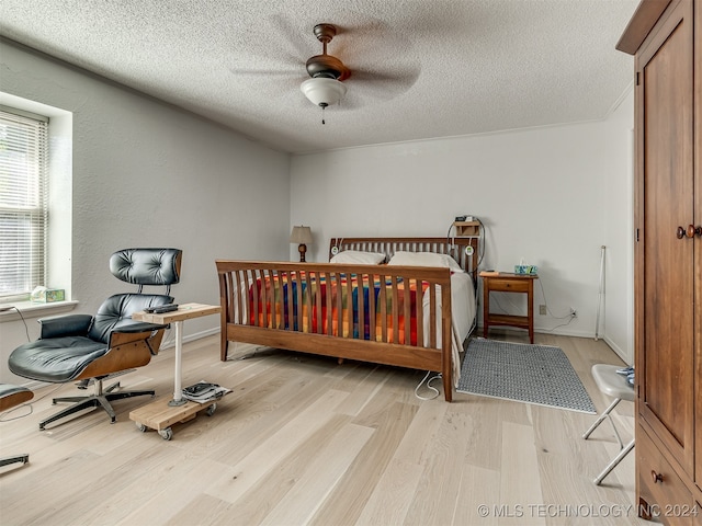 bedroom with a textured ceiling, light wood-type flooring, and ceiling fan