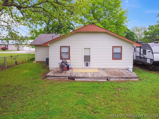 rear view of house with central AC, a deck, and a yard